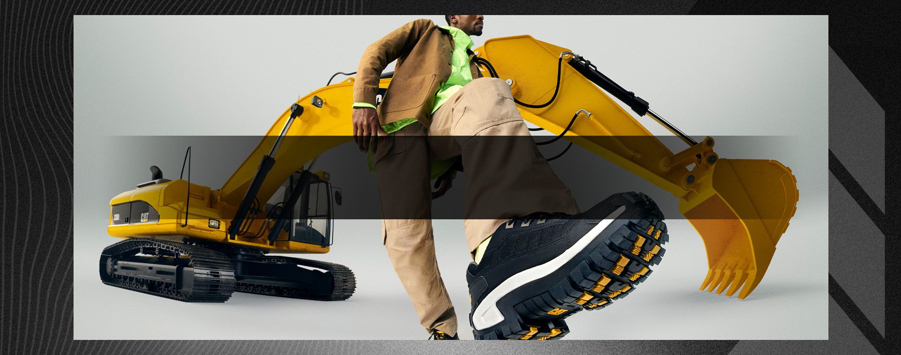 Dressed in khaki, standing in front of an excavator, showing off a black & white Invader sneaker.