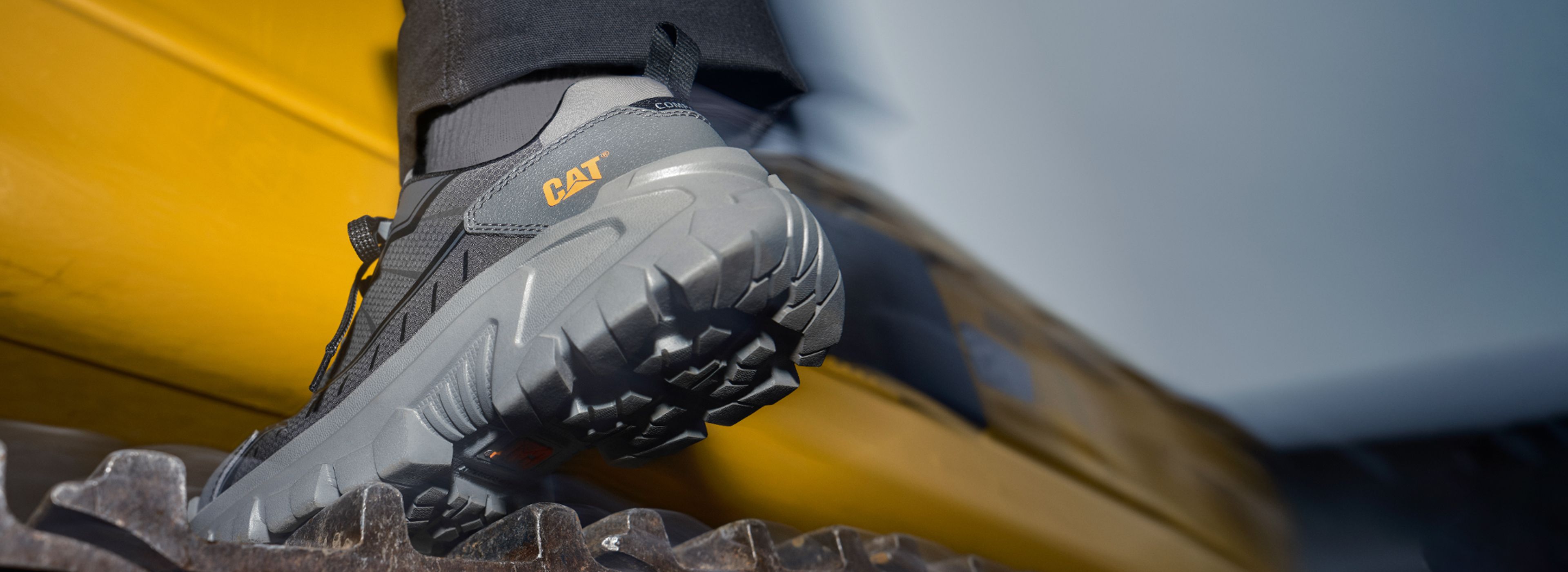 Foot wearing Invader Sport Work Shoe climbing on a large tire.