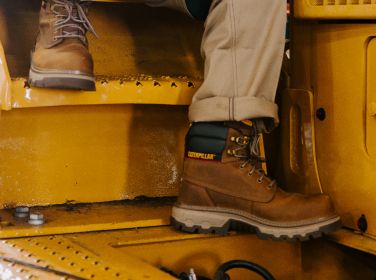 Brown boots on the steps of heavy machinery.