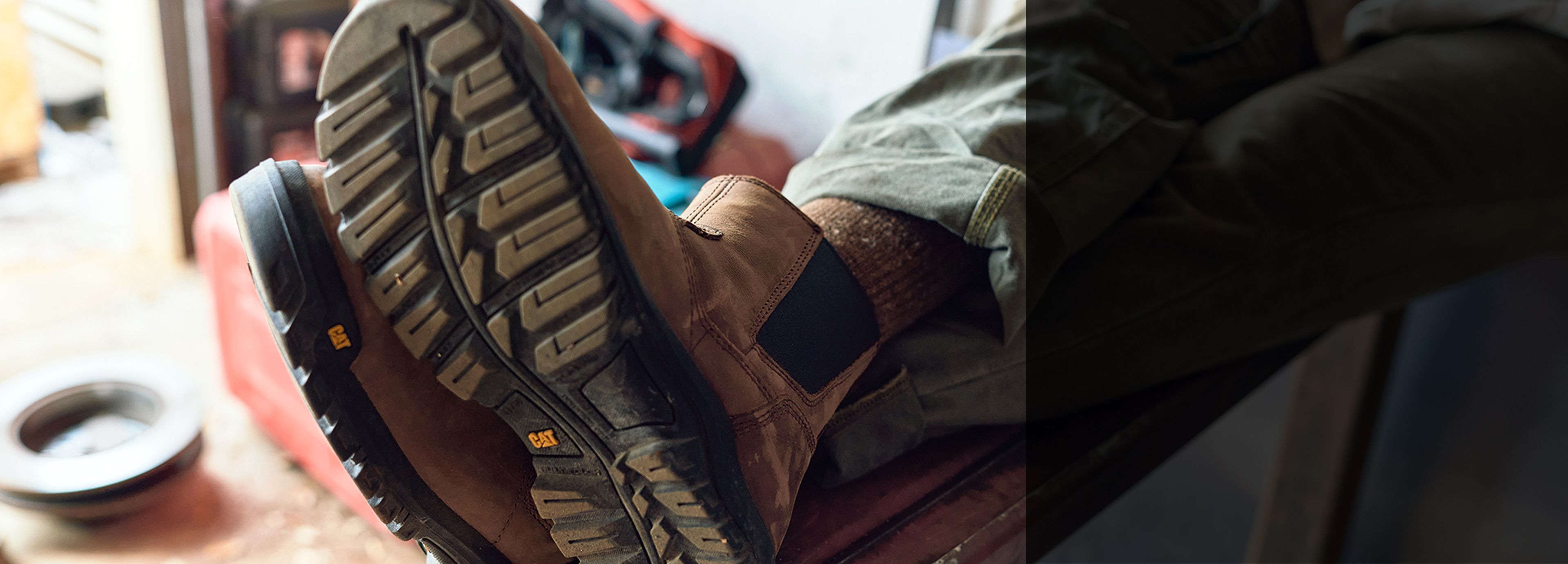 Feet wearing boots on a piece of iron box.